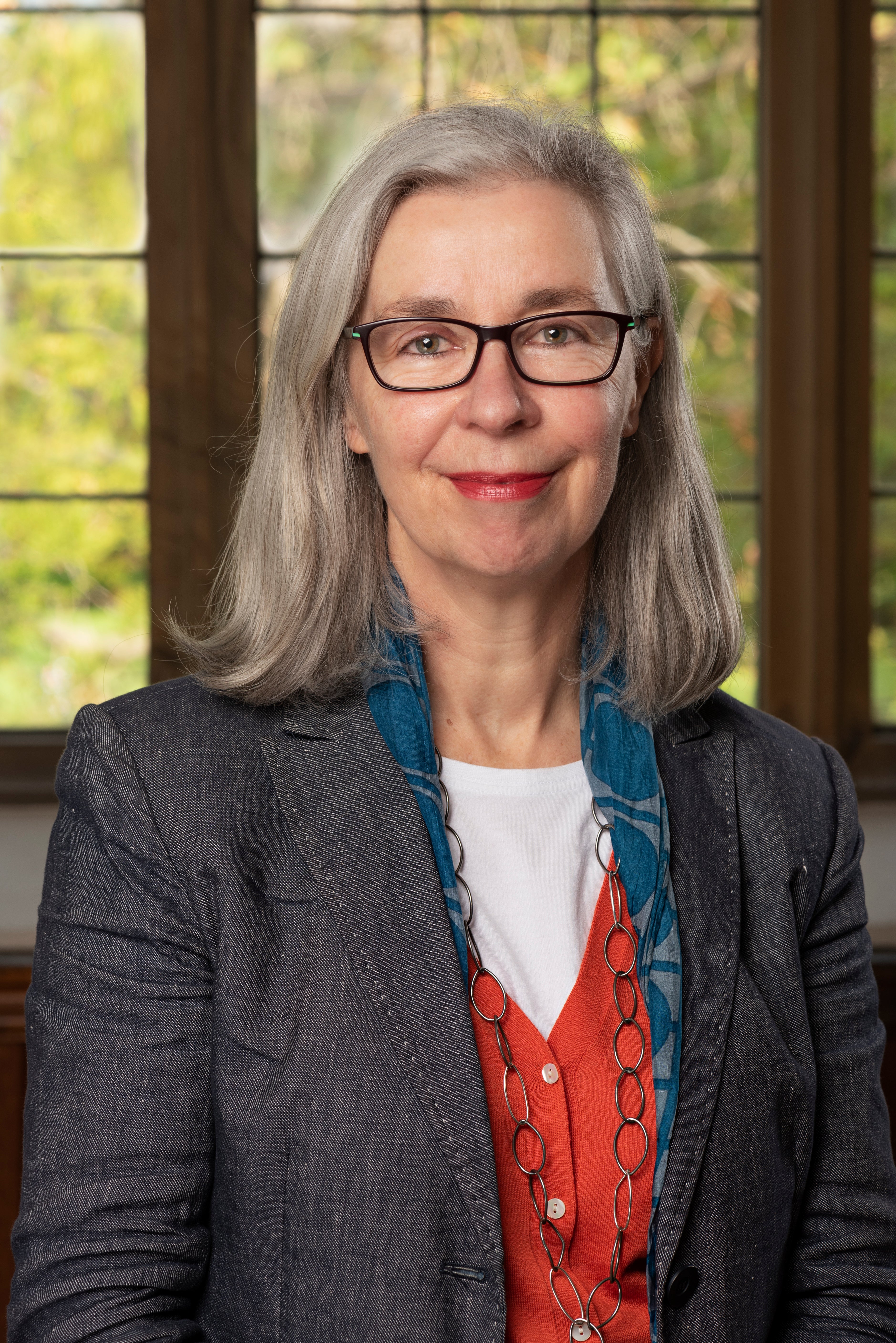Portrait of Claire Roberts Portrait of a woman with glasses in a gray jacket and red vest.