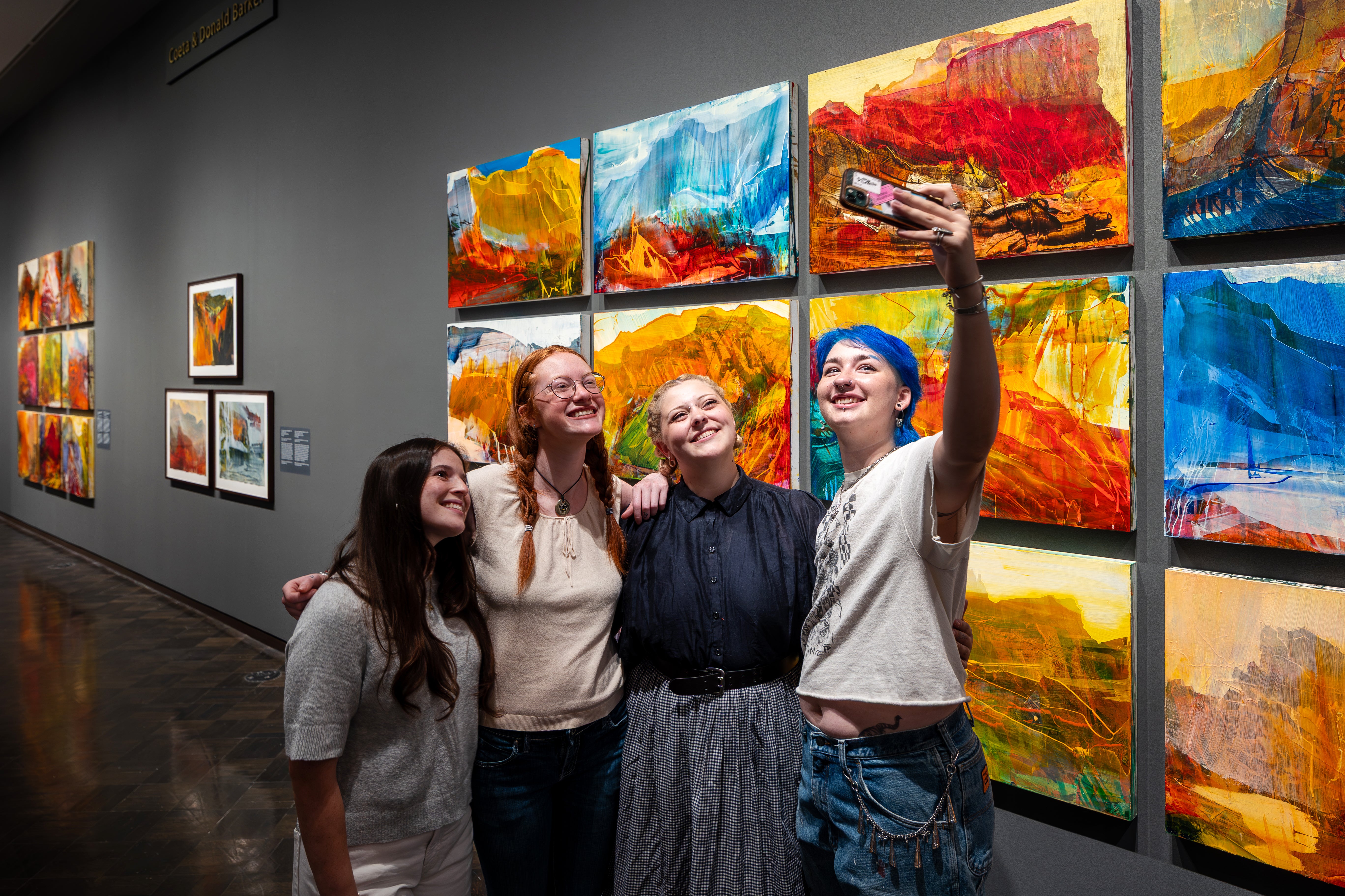 Installation image of James Lavadour: Land of Origin University students take a selfie in front of a James Lavadour grid painting