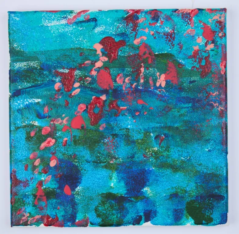 An abstract acrylic painting on a canvas with a bright, textured surface. The background is a mix of various shades of blue and teal, with some dark green. Over the background, there are numerous small splatters and drips of red and pink paint. The texture appears coarse, with some areas of thicker paint application.