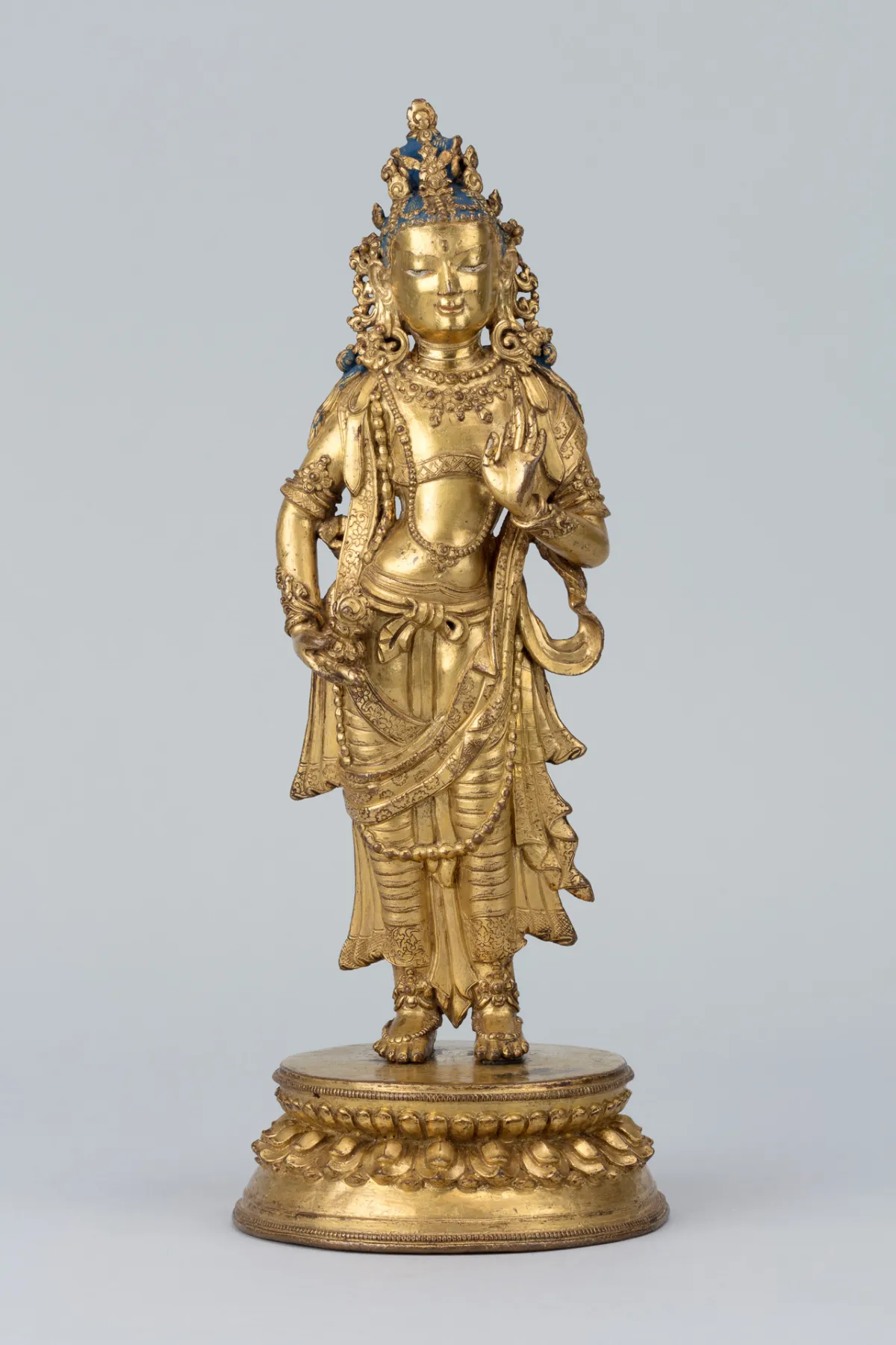 Gold statue of a Himalayan goddess on a grey background