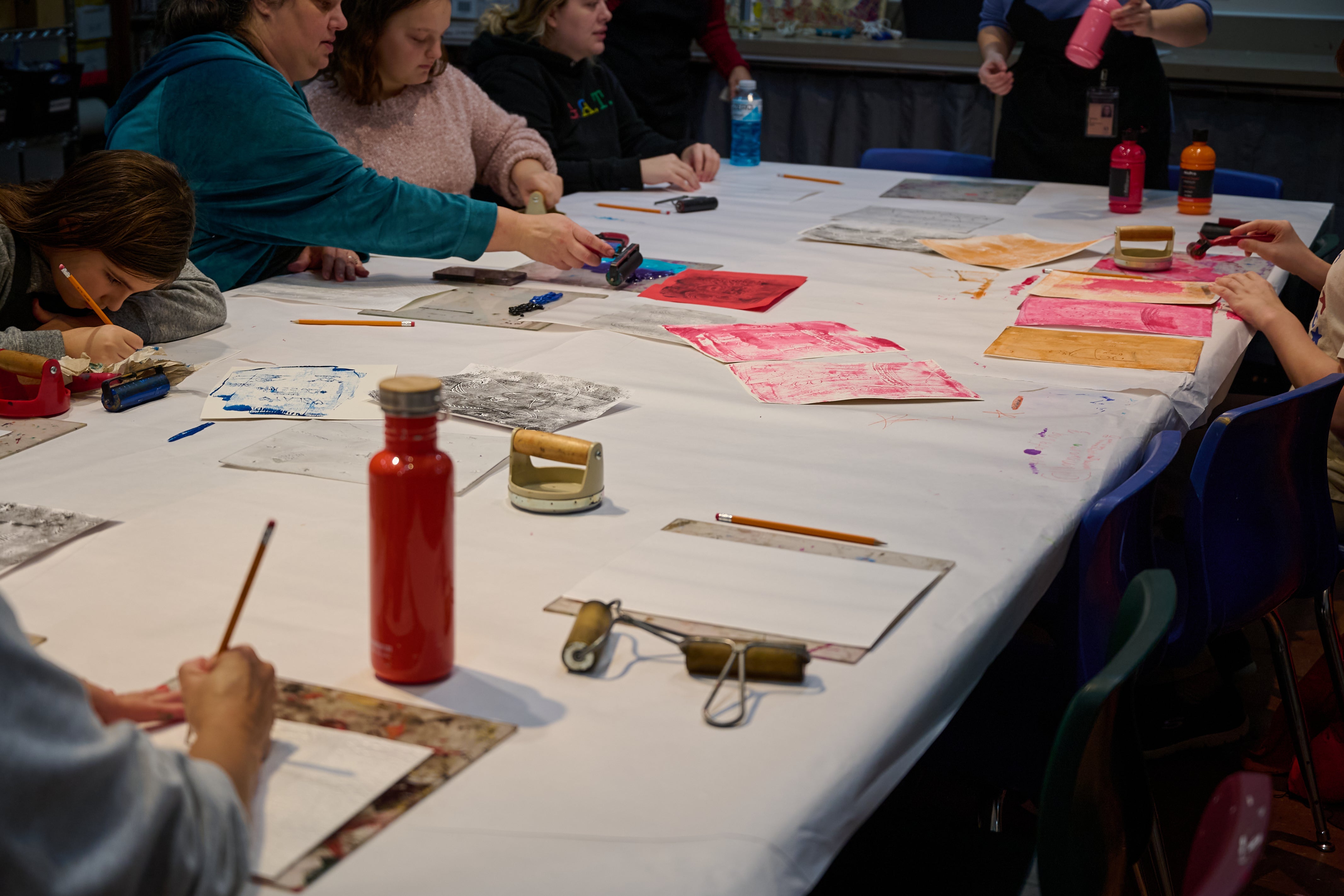 VSA Arts Access Program A long white table is covered with people making art and art supplies.