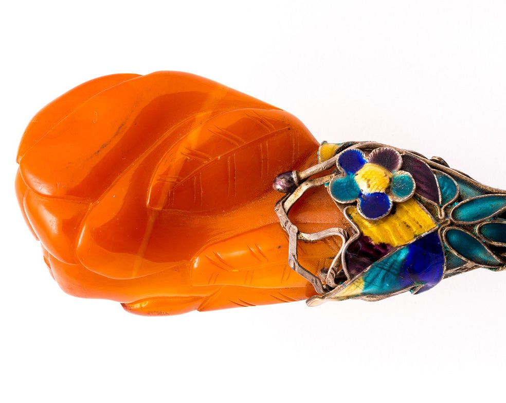 Carved orange gem with yellow and blue metalwork 