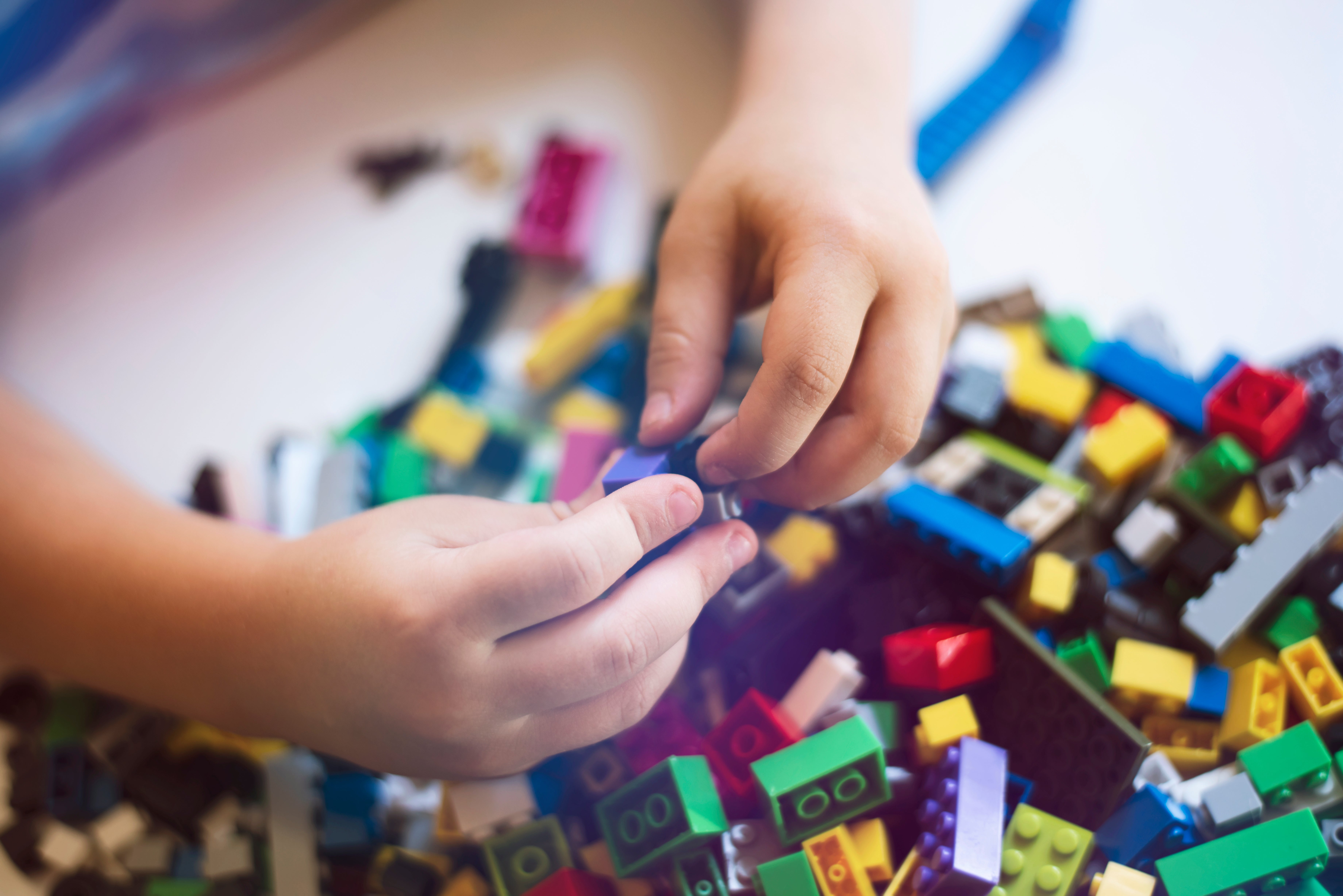 Small hands sort through a pile of brightly colored pile of legos