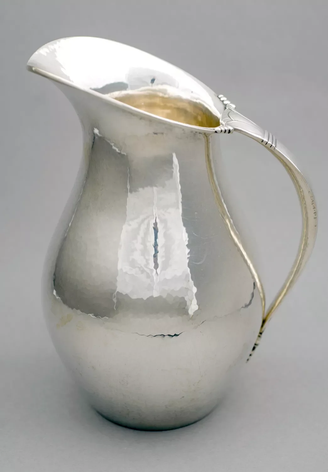 A silver pitcher on a grey background.